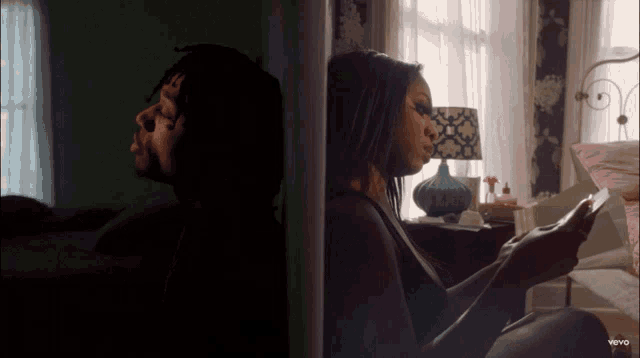 a man and a woman are sitting next to each other in a bedroom and the woman is looking at her phone