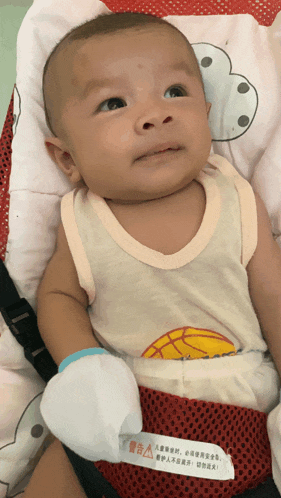 a baby wearing a white tank top with a basketball on it sits in a bouncer