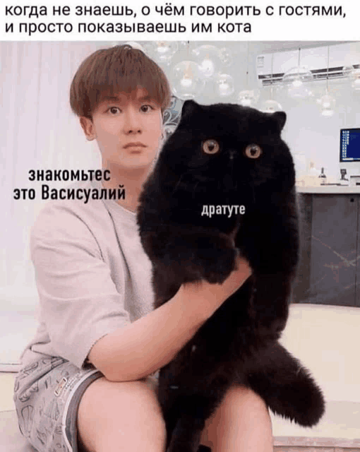 a man is holding a black cat in his arms with a caption in russian