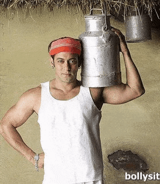 a man in a white tank top is holding a milk can on his shoulder