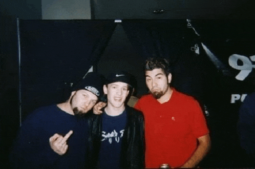 three men are posing for a picture and one of them is wearing a shirt that says sonic