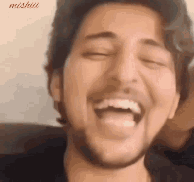 a close up of a man laughing with his tongue out .