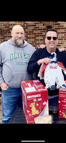 a man wearing an olivet basketball sweatshirt is standing next to another man