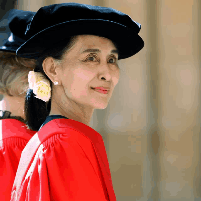 a woman wearing a red gown and a black hat