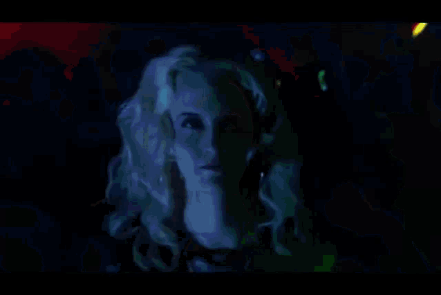 a woman with blonde hair is standing in front of a crowd of people