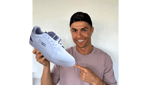 a man holds up a pair of white shoes with the letters reebok on them