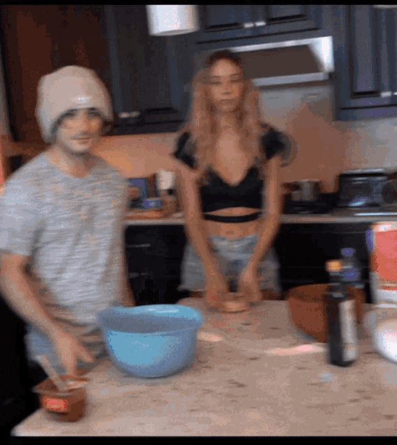 a man and a woman are preparing food in a kitchen with a bowl that says ' heinz ' on the front