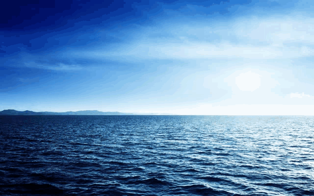 a large body of water with mountains in the background and a blue sky