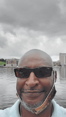 a man wearing sunglasses and a face mask is smiling