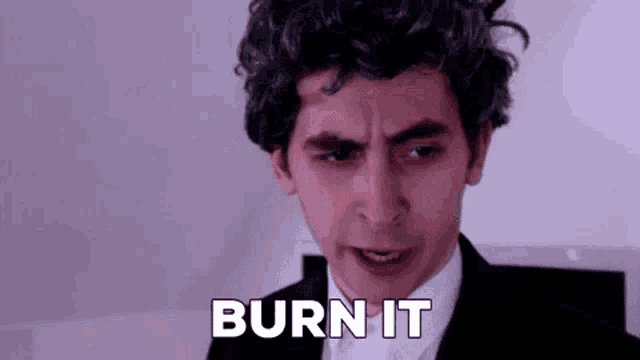 a man with curly hair is making a funny face and saying burn it .
