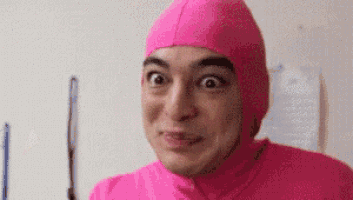 a man wearing a pink suit and pink hat is making a funny face .