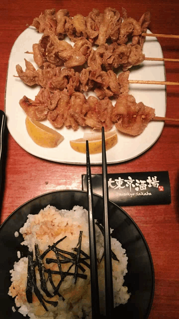 a plate of food with chopsticks next to a plate of rice