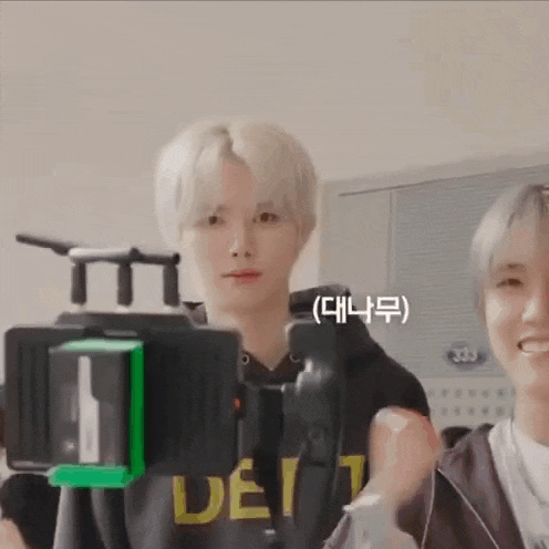 a man is standing in front of a camera while a woman looks on .