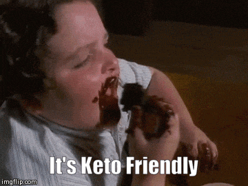 a man is eating a chocolate donut with the words " it 's keto friendly " above him