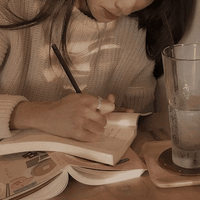 a woman writes in a notebook with a ring on her finger