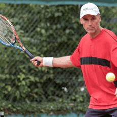 a man in a red shirt is holding a tennis racquet and a ball .