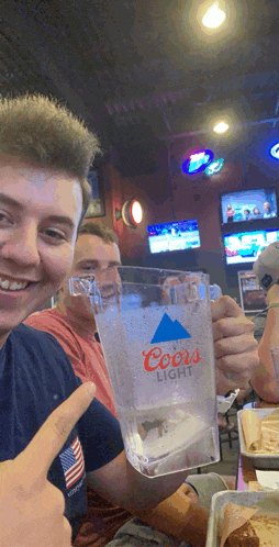 a man holds a coors light glass in his hand