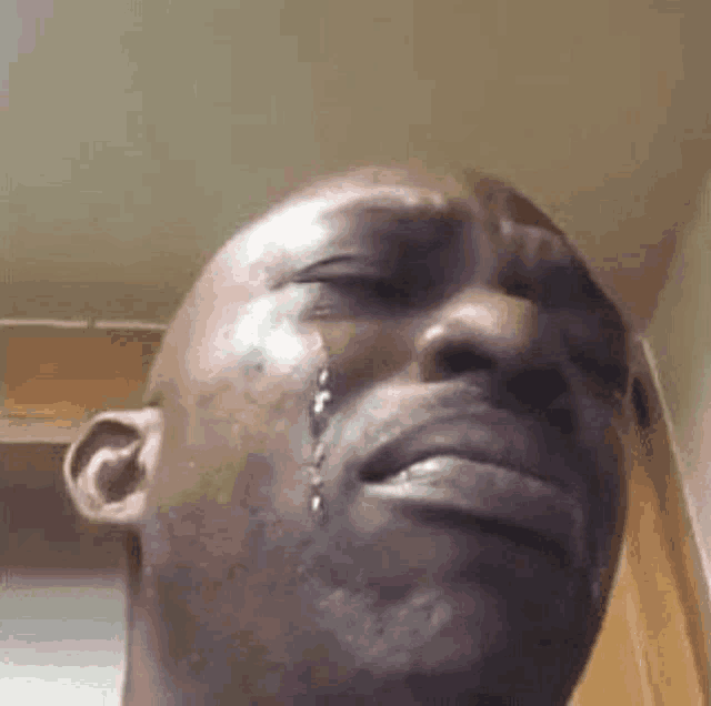 a close up of a man crying with tears running down his face .