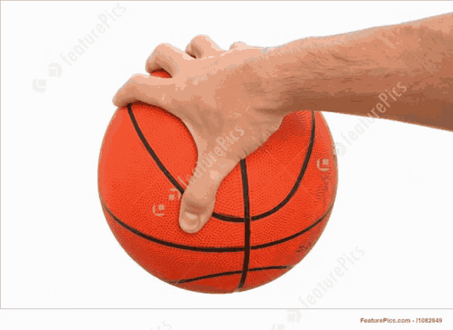 a man 's hand is holding a basketball with his thumb