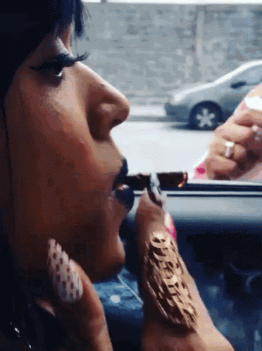 a woman is smoking a cigarette in a car while wearing a watch that says oreo on it