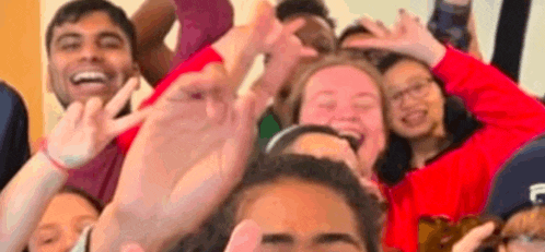 a group of people are posing for a picture with their hands up in the air .