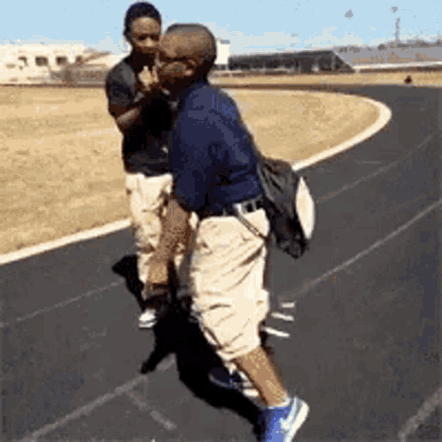 two men are standing next to each other on a track and one of them is carrying a backpack .