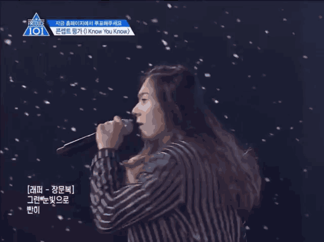 a woman singing into a microphone with a snowy background behind her