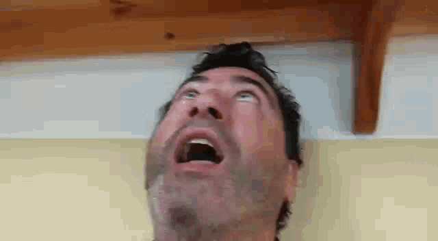 a man is looking up at the ceiling with his mouth open .