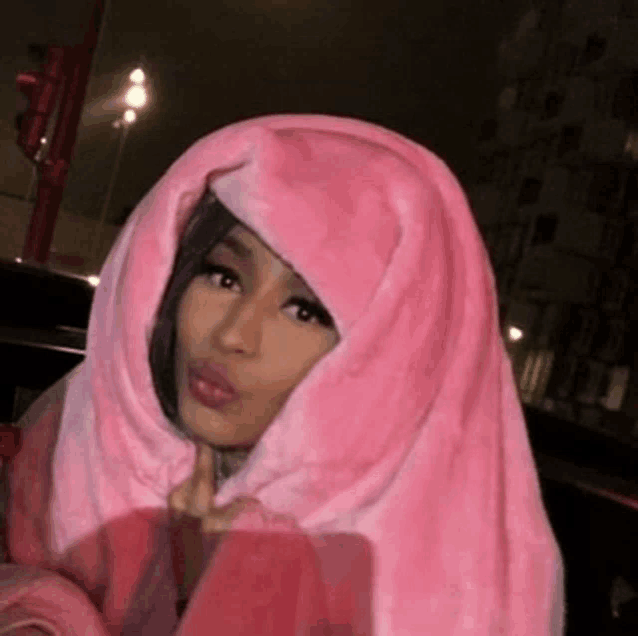 a woman is wrapped in a pink blanket and making a funny face .