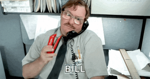 a man talking on a telephone with the word bill written on his shirt