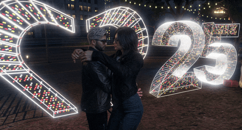 a man and a woman are hugging in front of a sign that has the number 25 on it