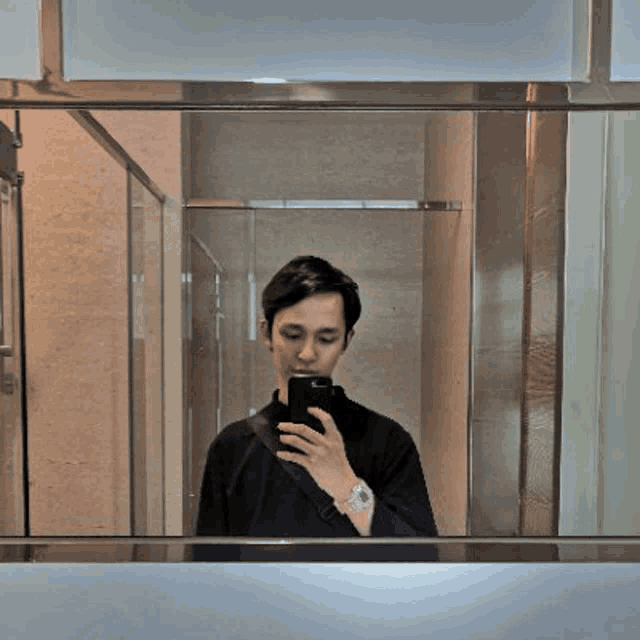 a man is taking a selfie in a bathroom mirror