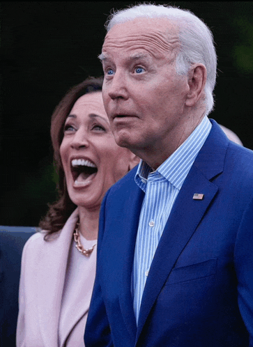 a man in a blue suit and a woman in a pink coat laugh together