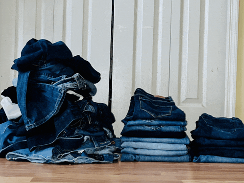 a pile of jeans sits on a wooden floor