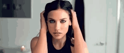 a woman is looking at her hair in the mirror .