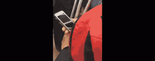 a person is holding a cell phone next to a red ribbon