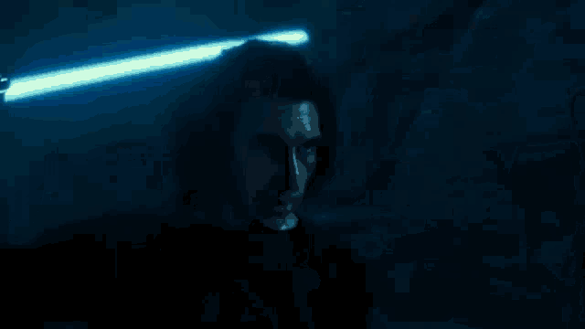 a group of men in black armor are standing next to each other in a dark room with a red light behind them .