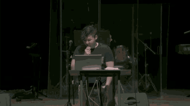 a man sitting at a desk with a laptop and a yamaha keyboard in the background
