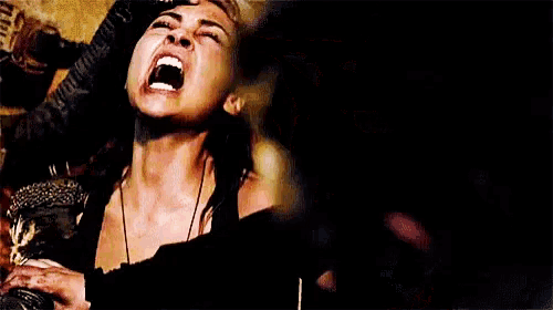 a woman is screaming in a dark room while sitting on a chair .