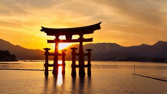 the sun is setting behind a torii gate in the middle of a body of water