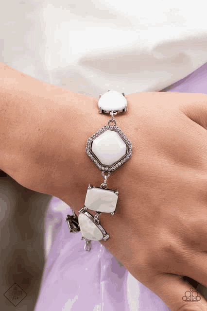 a woman wearing a bracelet with white stones and rhinestones on her wrist