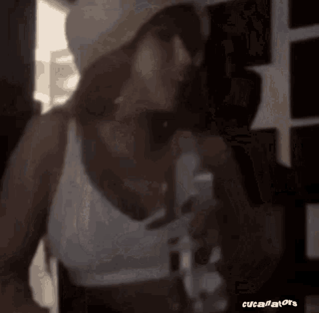 a woman wearing a hat and sunglasses is holding a glass of water .
