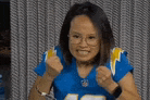 a woman wearing a blue jersey and glasses is making a fist gesture .