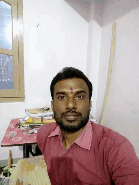 a man with a red dot on his forehead is taking a selfie