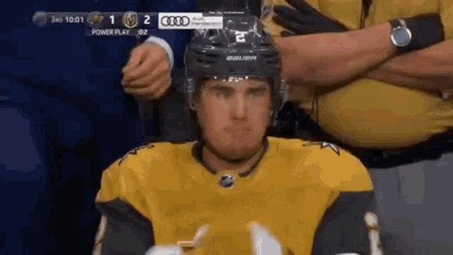 a hockey player wearing a helmet and a yellow jersey is sitting in the stands .