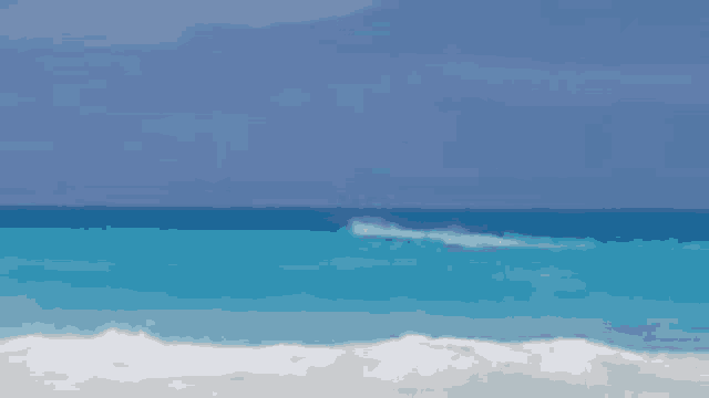 a blurred image of a beach with waves crashing on the sand .