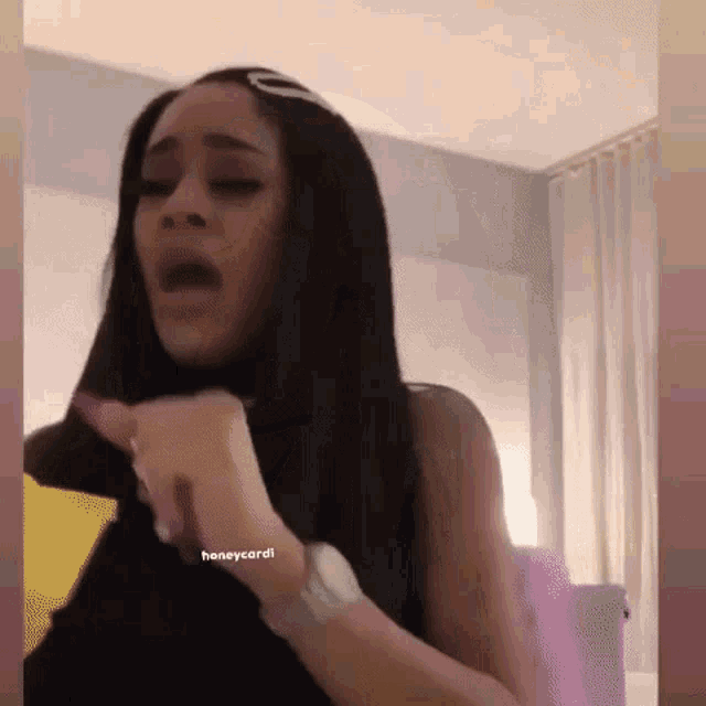 a woman with long black hair is making a funny face in a bedroom .