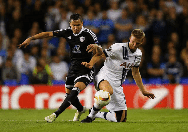 two soccer players are playing on a field with a sign that says credit in the background