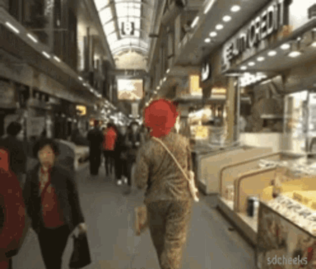 a woman wearing a red hat is walking down a busy street in front of a store that says euro credit