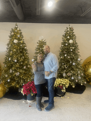 a man and woman standing in front of a christmas tree